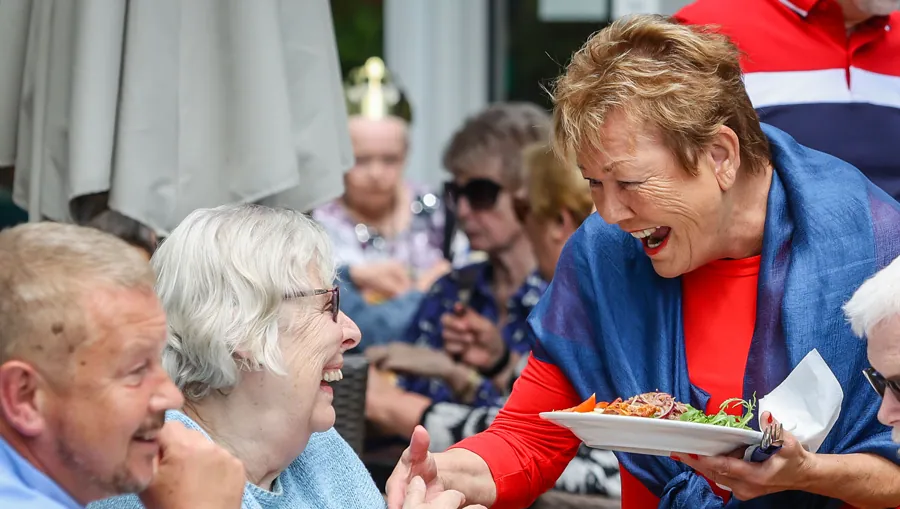 A resident being served lunch at a garden party