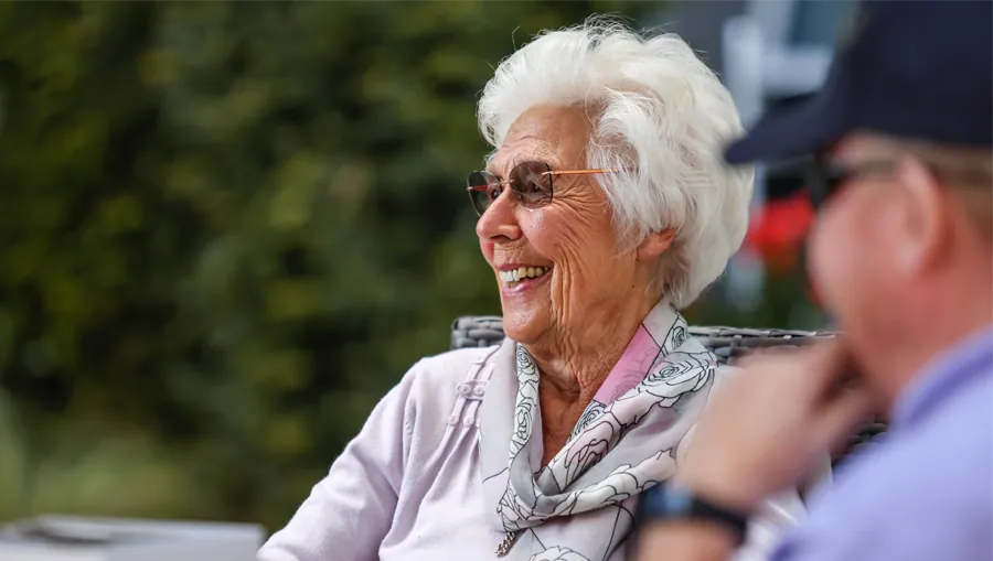 A resident smiling in a community garden
